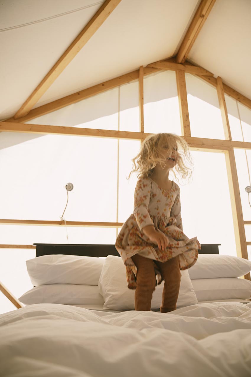 Little girl jumping on a bed in a tent